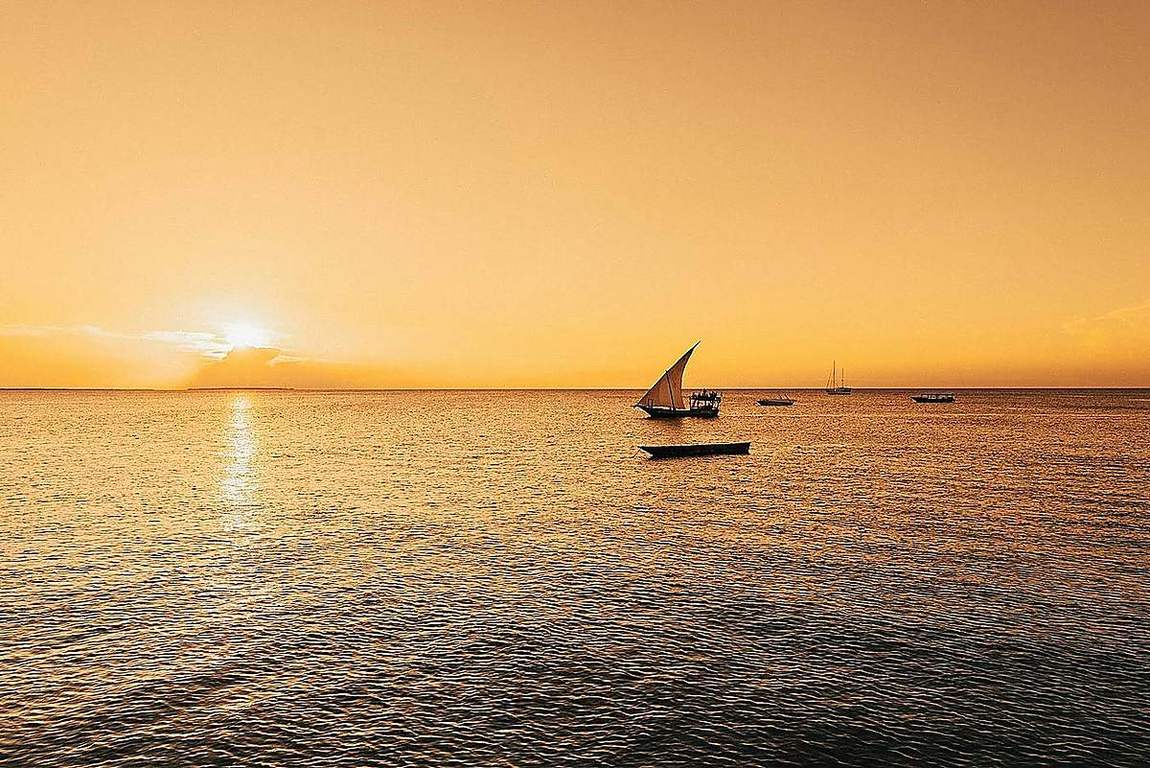 Traditional dhow sailing at sunset off Zanzibar